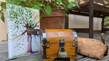 Wooden chest, painting, and pouch outdoors.