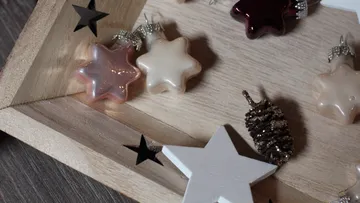 Sternförmige Ornamente und Tannenzapfen auf Tablett.