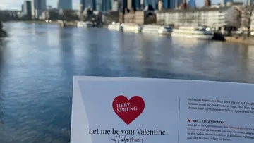 Card with text held in front of river view.