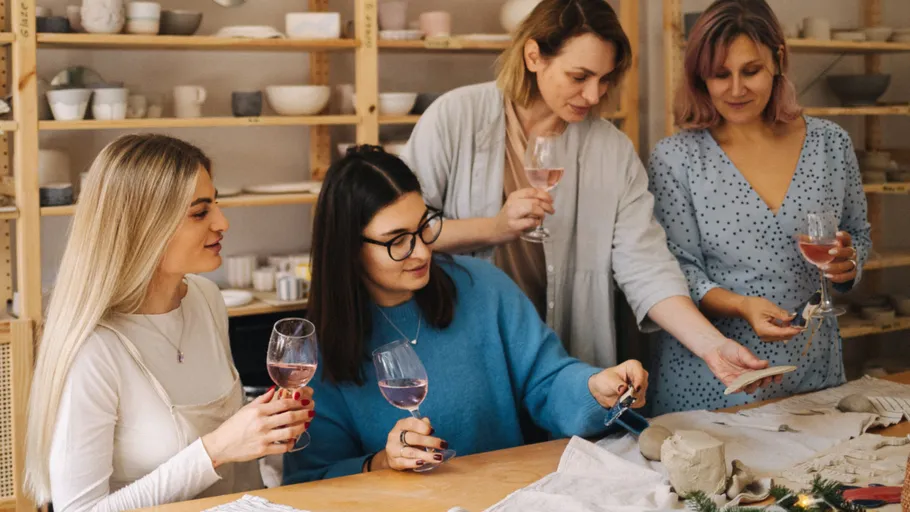 Four women enjoying wine in pottery studio.
