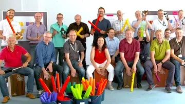 Group playing percussion instruments in office.