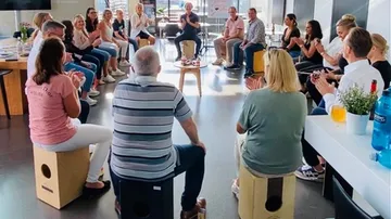 Gruppe, die im Kreis sitzt und drinnen klatscht.