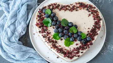 Herzförmiger Kuchen mit Blaubeeren auf einem Teller.