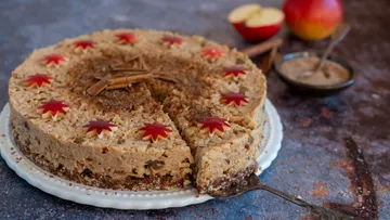 Dekorativer Apfelkuchen mit geschnittenem Stück, rustikaler Tisch.
