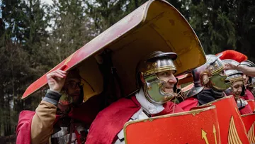 Reenactors in römischer Rüstung, die draußen Schilde halten.