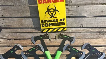 Axes with green handles on wooden surface, zombie warning sign.