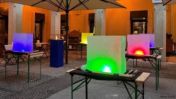 Bunte Eisblöcke, die draußen auf Tischen leuchten.