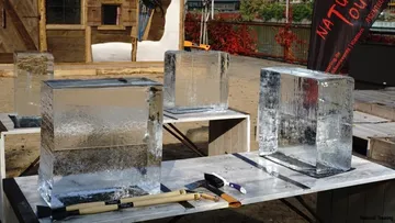 Eisblöcke auf Tischen mit Werkzeugen im Freien.