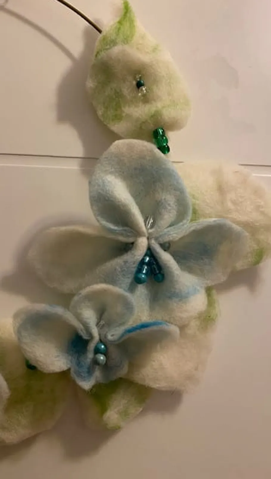Felt flower decoration with beads on white surface.
