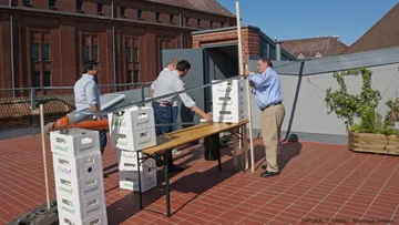 Männer beim Zusammenstellen eines Tisches auf der Dachterrasse.