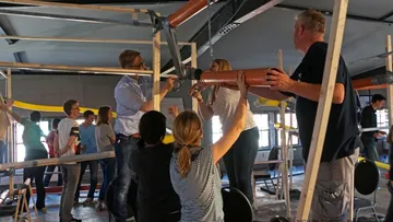 Die Gruppe baut drinnen ein großes Gerät zusammen.