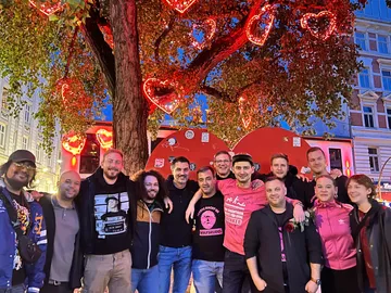 Group poses under tree with red heart lights.