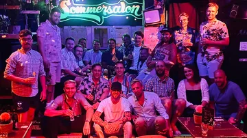 Gruppe von Menschen, die in einer Bar mit Neonlichtern posieren.