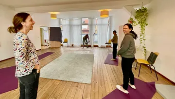 Women chatting in a yoga studio with mats.