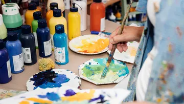 Person, die im Kunstatelier Farbe auf einer Palette mischt.