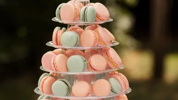 Tiered stand with pink and green macarons outdoors.