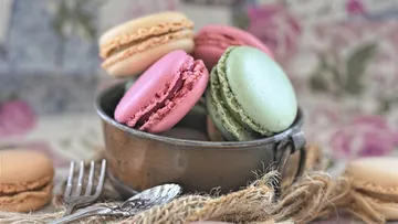 Colorful macarons in rustic metal cup.