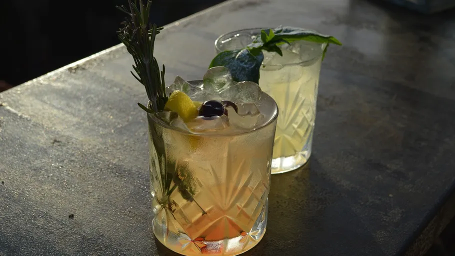 Two cocktails with garnishes on a table.