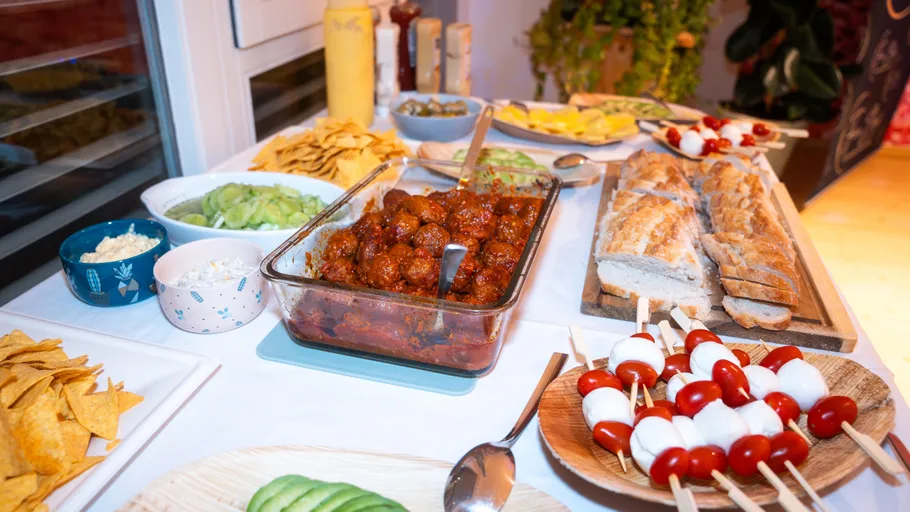 Buffet mit Fleischbällchen, Brot und Spießen in einer Küche.