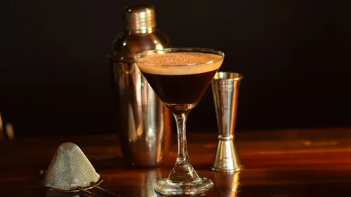 Espresso-Martini und Barutensilien auf einer Holztheke.