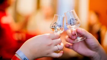Two people clinking glasses at an event.