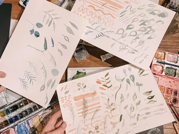Three drawings with plant patterns lie on a table.
