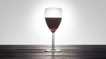Red wine glass on wooden surface.