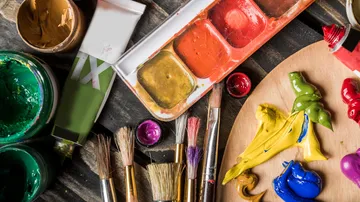 Paints, brushes, and palette on a table.