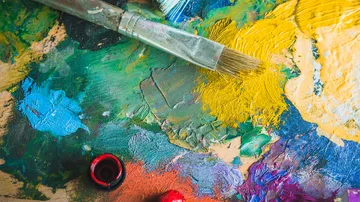 Paintbrush on colorful palette with paints