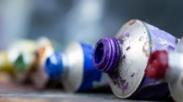Paint tubes with spilled colors on surface.
