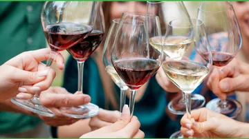 Hands holding wine glasses in celebratory toast.