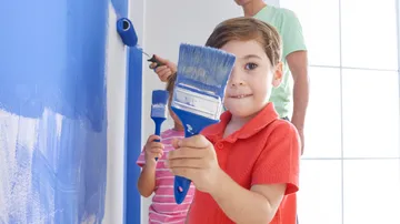 Kinder, die drinnen Wände blau streichen.