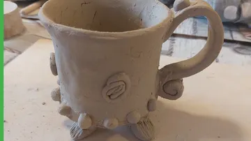 Clay mug with decorative patterns on table.