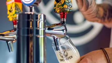 Person pouring beer from tap into glass.