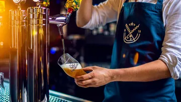 Bartender pouring beer into glass at bar.