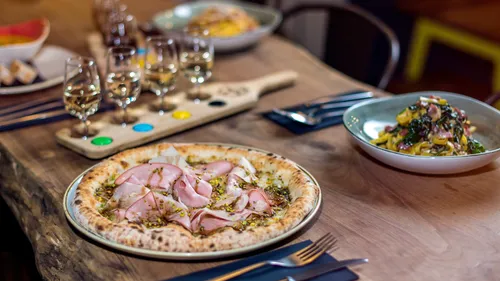 Gourmet pizza and pasta with wine on a wooden table.