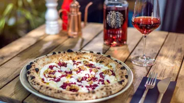 Gourmet pizza with wine on wooden table.