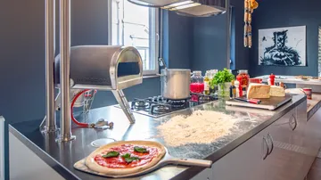 Kitchen with pizza dough, oven, and ingredients.