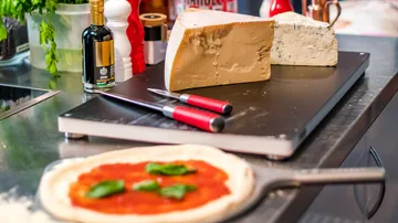 Cheese block and pizza in kitchen.