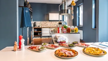 Plates of pizza and meats in a modern kitchen.