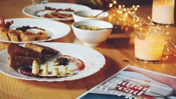 Plate of Indian food surrounded by candles and a magazine.