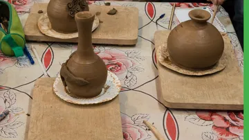 Drei Tontöpfe auf einer geblümten Tischdecke.