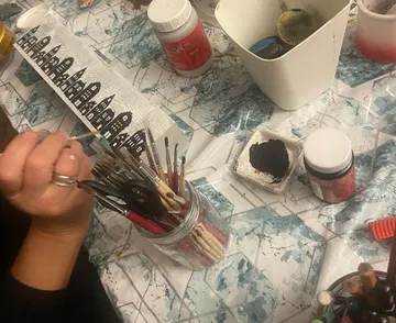 Person, die mit Pinseln auf Papier malt.