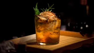 Cocktail im Glas mit Garnitur auf einem Holztablett.