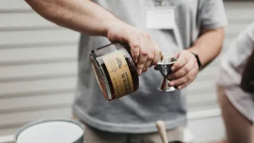Person, die drinnen Whiskey in den Jigger gießt.