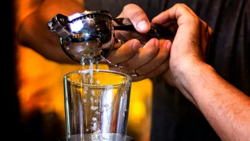 Hand squeezing lemon into glass.