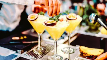 Bartender garnishing tropical cocktails at bar.