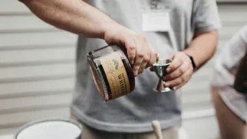 Person pouring whiskey into a jigger.