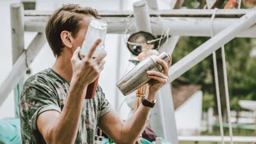 Person holding cocktail shaker outdoors.