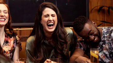 Three people laughing joyfully in a bar.